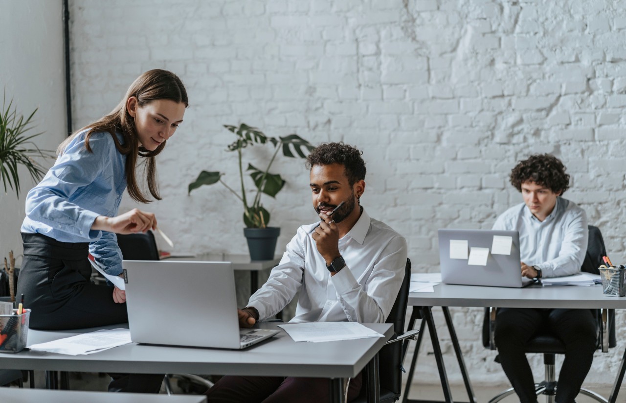 3 people on computers in an office chatting