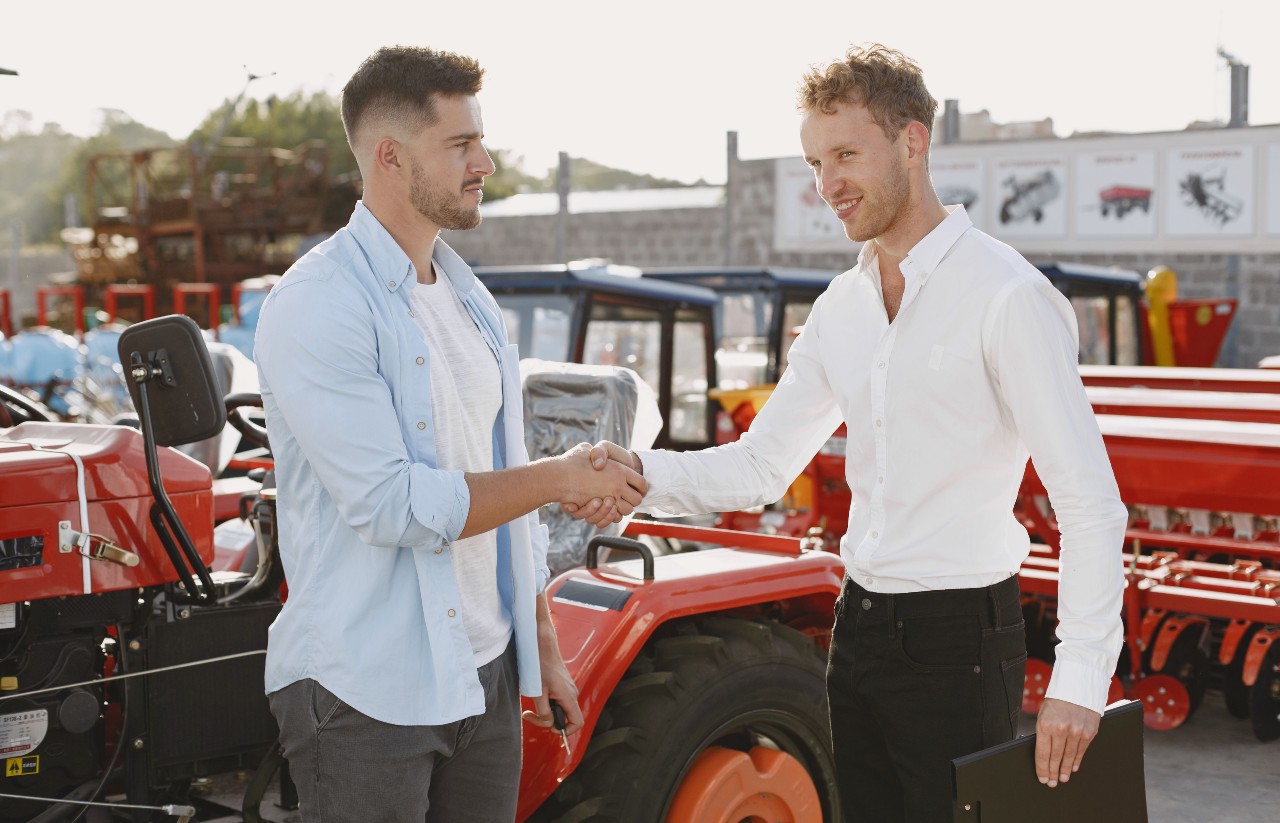 Two people shaking hands beside business machinery and equipment